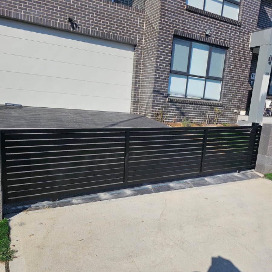 Black horizontal slat aluminium sliding gate across a townhouse driveway