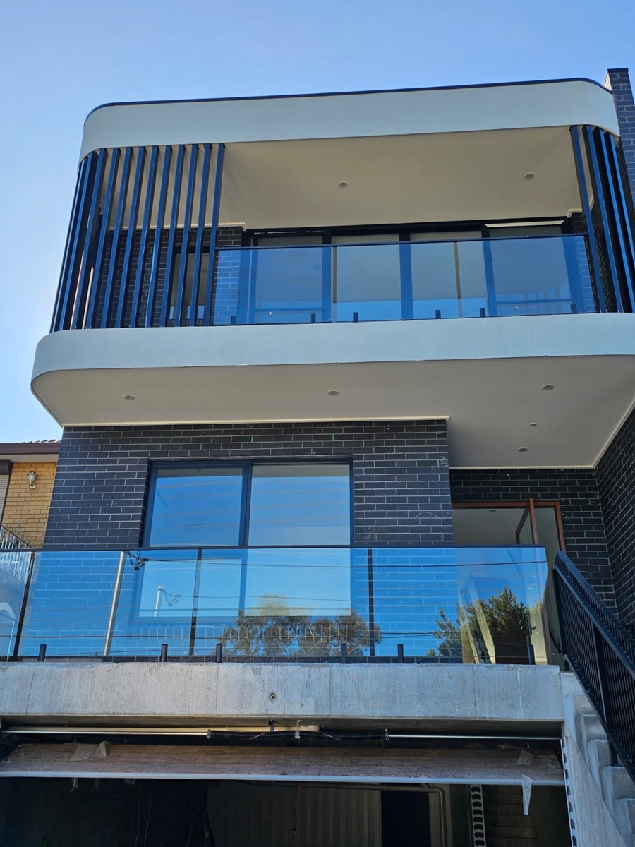 Glass balcony balustrades on two levels of a modern Sydney duplex with black slat screens