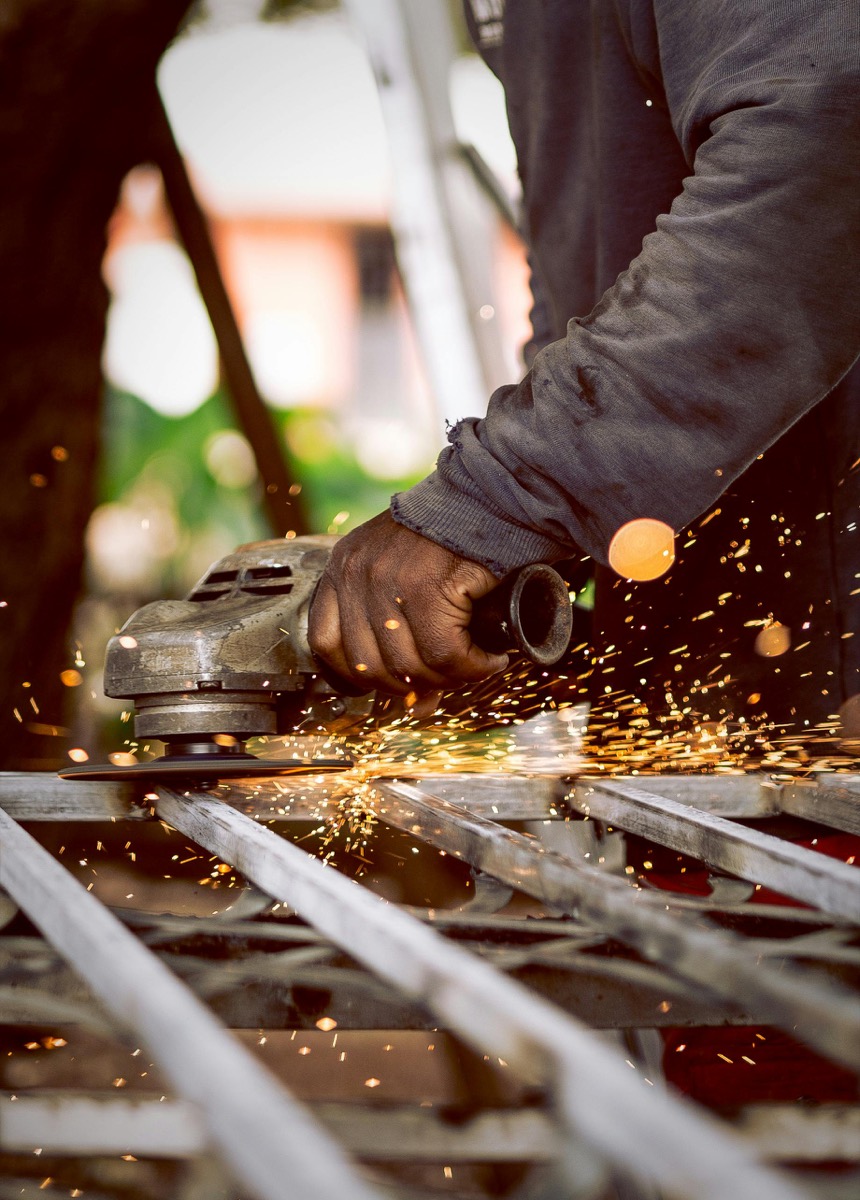 Angle grinder finishing the welds on a fabricated metal gate frame