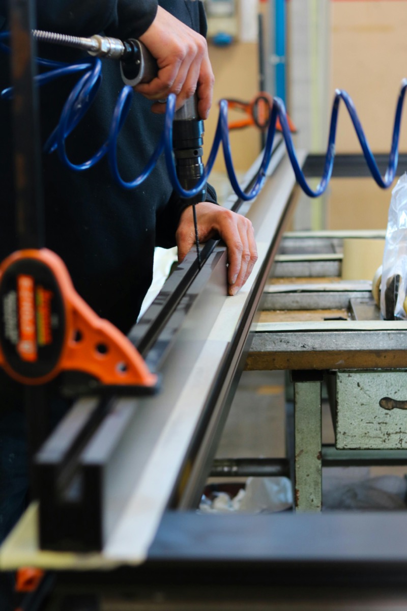 Tradesperson marking measurements along an aluminium extrusion in the workshop