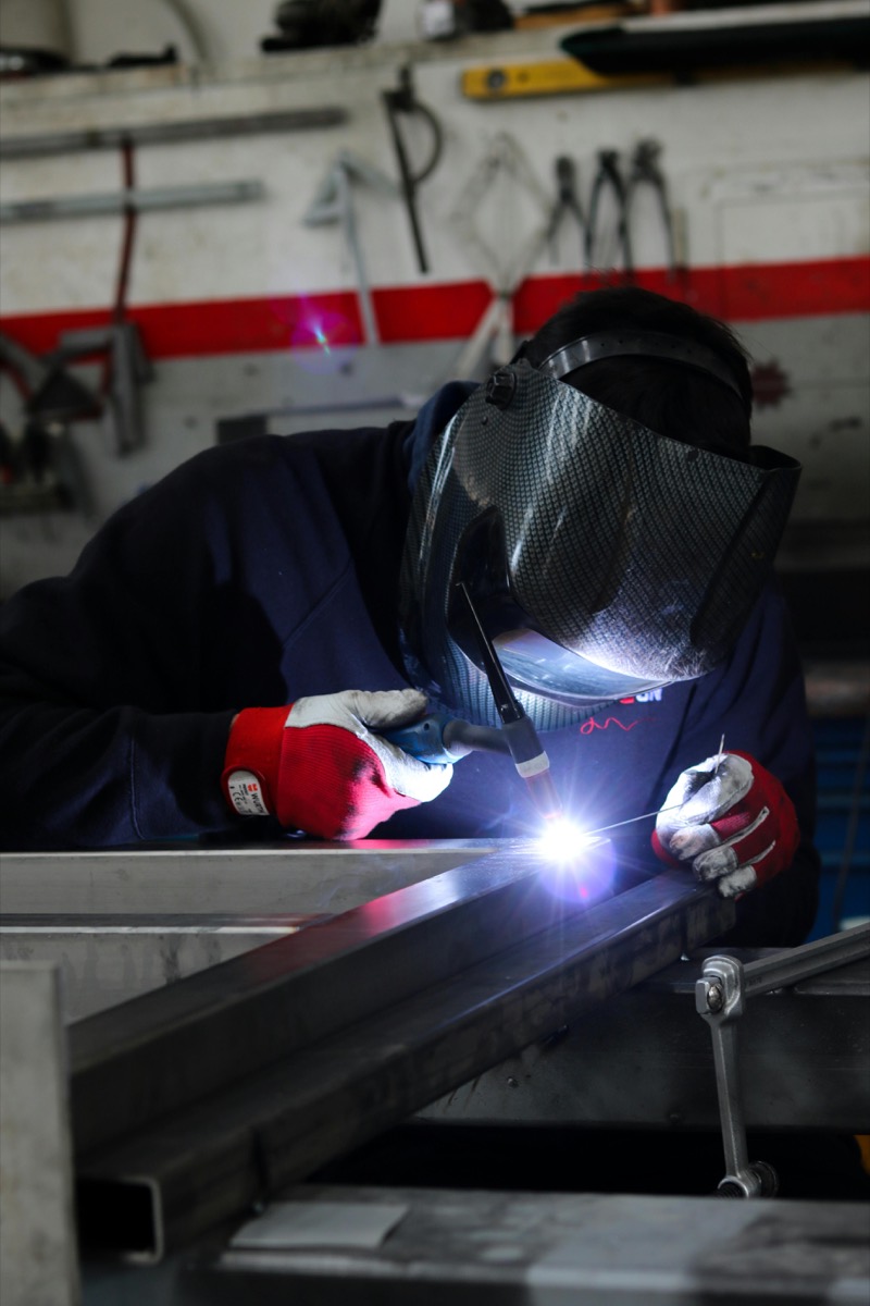Welder joining a steel frame with a TIG torch in the fabrication workshop