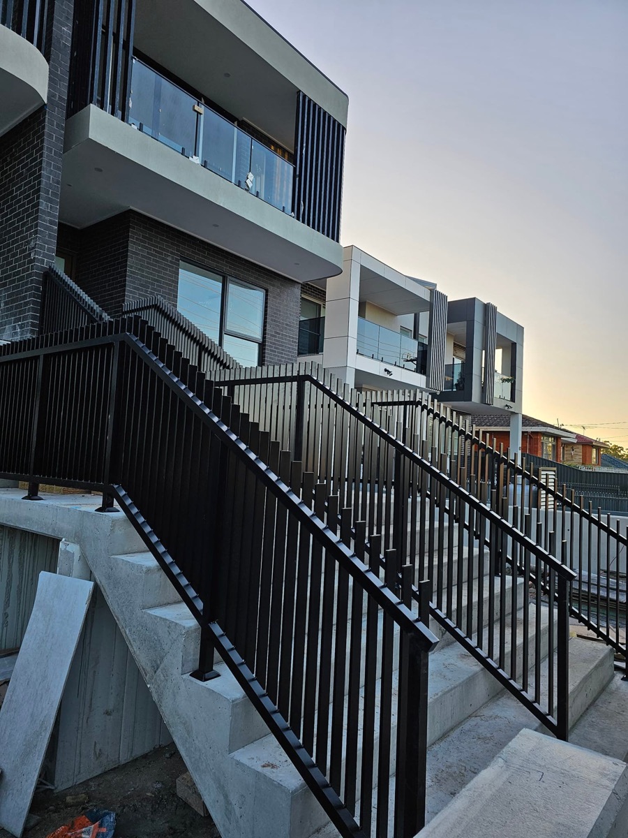 Black vertical blade balustrade running up external concrete entry stairs at a Sydney townhouse development